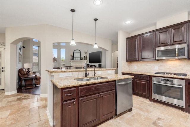 kitchen featuring a sink, arched walkways, stone tile floors, and stainless steel appliances
