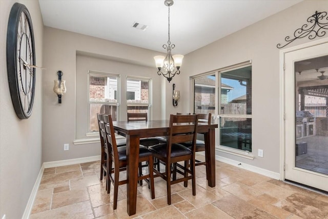 dining area with stone tile flooring, a notable chandelier, baseboards, and visible vents