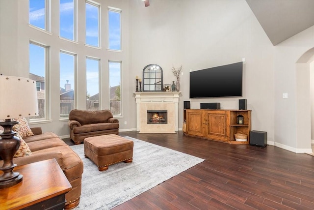living room with arched walkways, dark wood-style floors, baseboards, and a fireplace