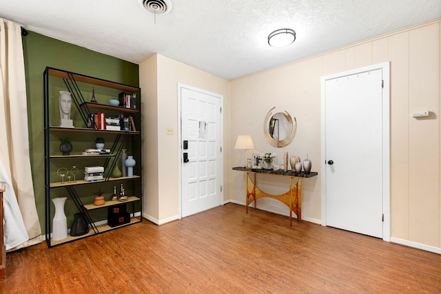 entrance foyer with visible vents, a textured ceiling, baseboards, and wood finished floors