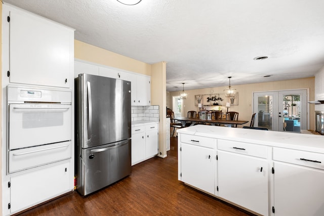 kitchen featuring white oven, dark wood finished floors, a warming drawer, freestanding refrigerator, and white cabinets