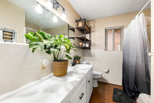 bathroom with tile walls, toilet, vanity, a textured ceiling, and wood finished floors