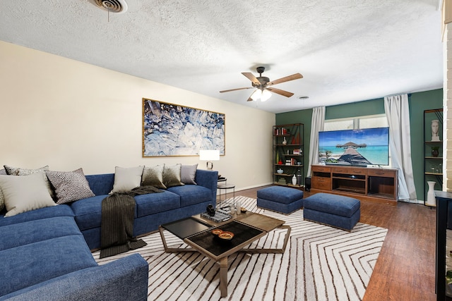 living room with ceiling fan, a textured ceiling, wood finished floors, and baseboards