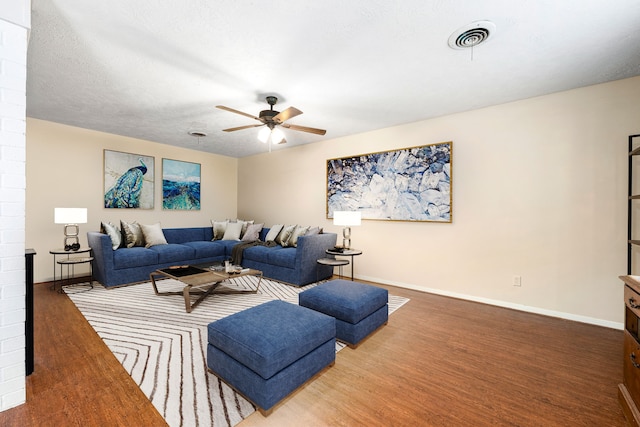 living area with visible vents, a ceiling fan, a textured ceiling, wood finished floors, and baseboards