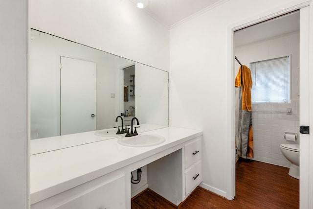 bathroom featuring toilet, wood finished floors, crown molding, vanity, and tile walls