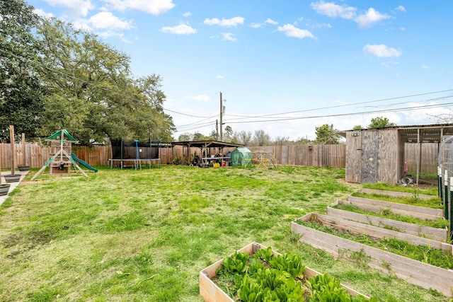 view of yard with a trampoline, a playground, a vegetable garden, and a fenced backyard