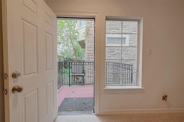 doorway to outside with carpet flooring and baseboards