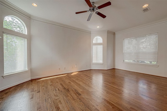 unfurnished room with baseboards, visible vents, crown molding, and wood finished floors