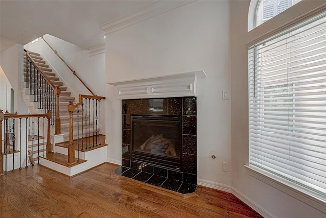 living room featuring stairs, baseboards, wood finished floors, and a tile fireplace