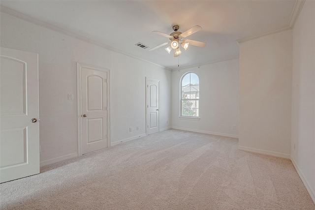 unfurnished room with a ceiling fan, visible vents, crown molding, and light carpet