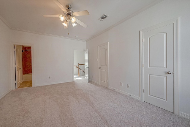 spare room with baseboards, carpet flooring, visible vents, and crown molding