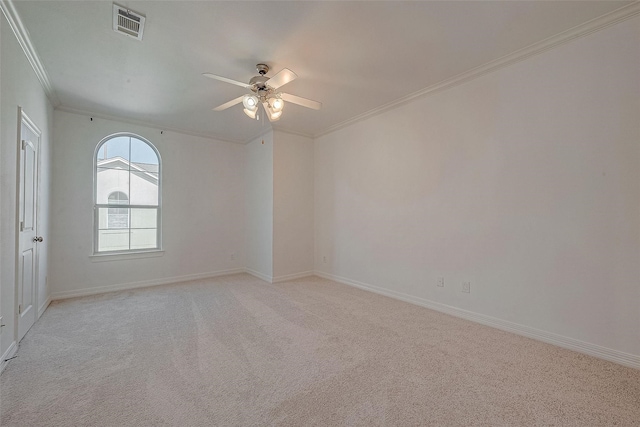 unfurnished room with ceiling fan, light colored carpet, visible vents, baseboards, and crown molding