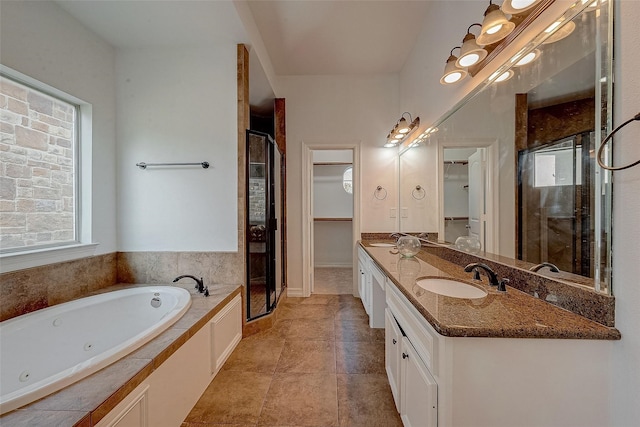 full bathroom with a walk in closet, double vanity, a sink, a shower stall, and a jetted tub