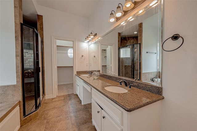 full bath with double vanity, a stall shower, a spacious closet, and a sink