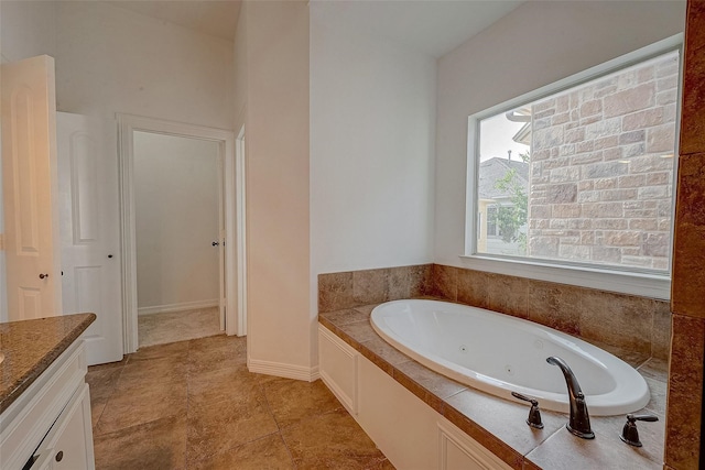 bathroom featuring baseboards, a tub with jets, and vanity