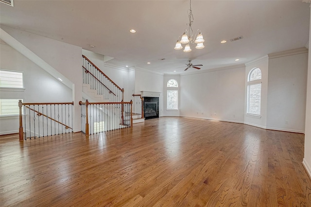 unfurnished living room with crown molding, a fireplace, wood finished floors, and a healthy amount of sunlight