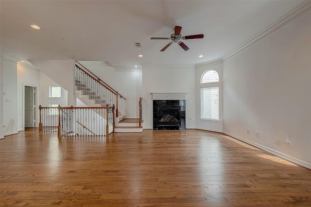 unfurnished living room with stairs, visible vents, baseboards, and wood finished floors