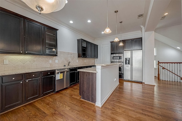 kitchen with dark wood-style floors, a center island, pendant lighting, glass insert cabinets, and built in appliances