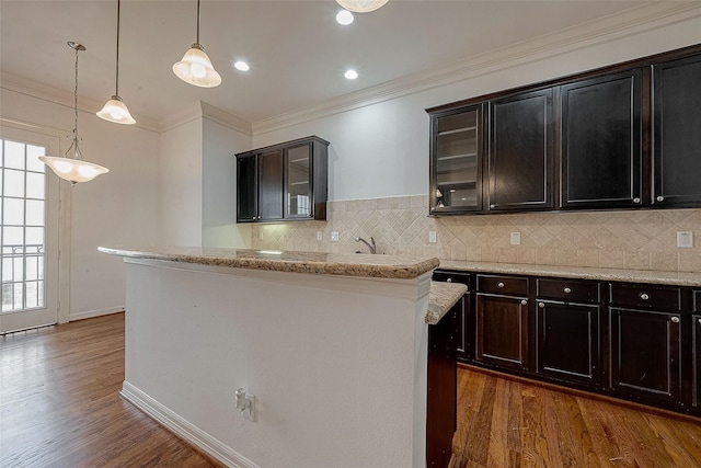 kitchen featuring dark wood-style floors, glass insert cabinets, decorative backsplash, and crown molding