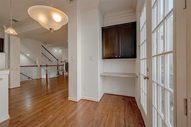 hallway with ornamental molding, light wood-style floors, and baseboards