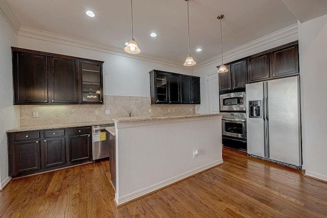 kitchen featuring hanging light fixtures, appliances with stainless steel finishes, ornamental molding, dark wood-style floors, and glass insert cabinets