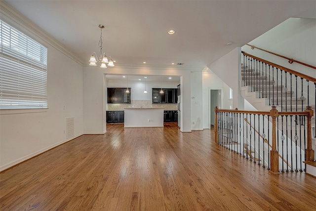 unfurnished living room with baseboards, recessed lighting, wood finished floors, and a notable chandelier