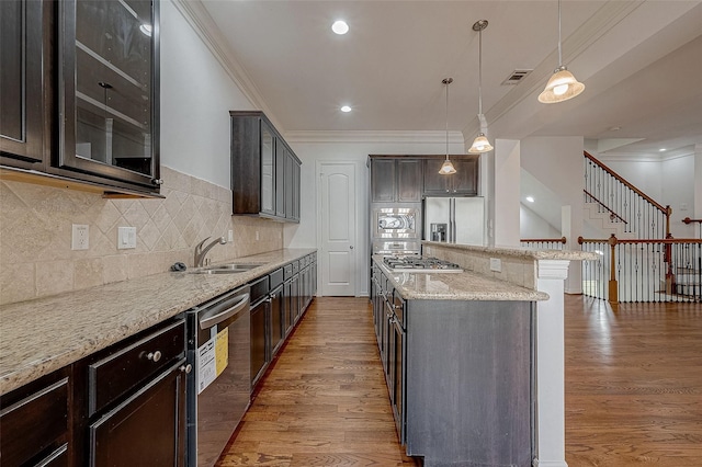 kitchen featuring wood finished floors, a kitchen island, appliances with stainless steel finishes, light stone countertops, and crown molding