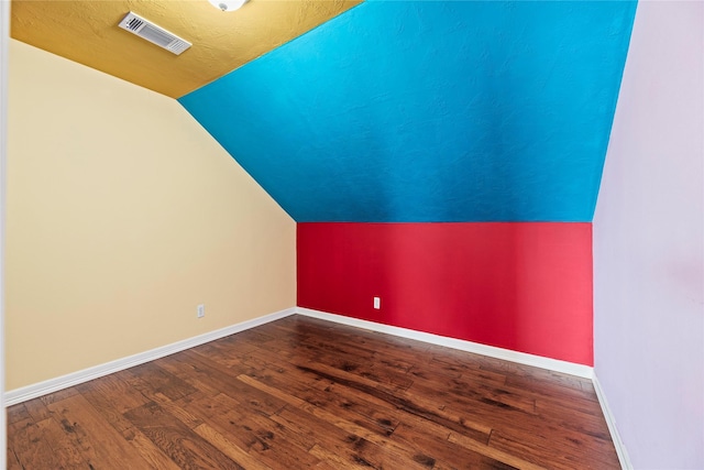 additional living space with visible vents, vaulted ceiling, baseboards, and wood finished floors