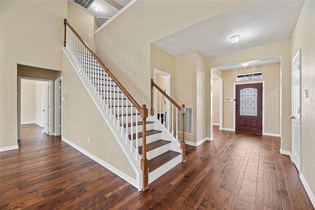 foyer featuring dark wood-style flooring, visible vents, baseboards, and stairs