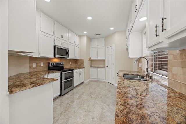 kitchen with stone counters, stainless steel appliances, a sink, white cabinets, and backsplash