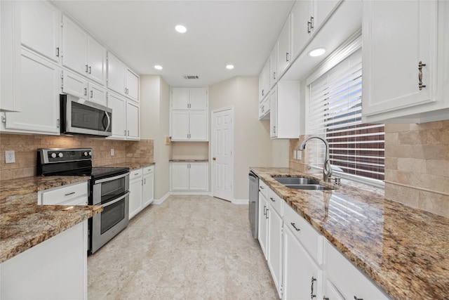 kitchen featuring appliances with stainless steel finishes, white cabinetry, a sink, and light stone countertops