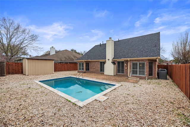 view of swimming pool with central AC unit, a storage unit, an outdoor structure, and a fenced backyard