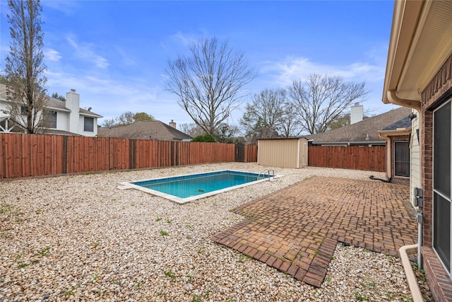 view of swimming pool with a patio area, an outdoor structure, a fenced backyard, and a storage shed