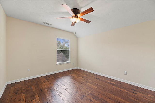 empty room featuring visible vents, dark wood finished floors, baseboards, ceiling fan, and vaulted ceiling