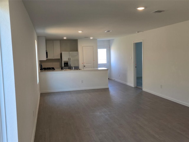 kitchen featuring visible vents, baseboards, dark wood finished floors, a peninsula, and stainless steel refrigerator with ice dispenser