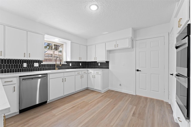 kitchen with stainless steel appliances, light wood-style floors, light countertops, and a sink