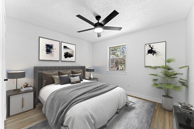 bedroom featuring light wood-style floors, ceiling fan, a textured ceiling, and baseboards