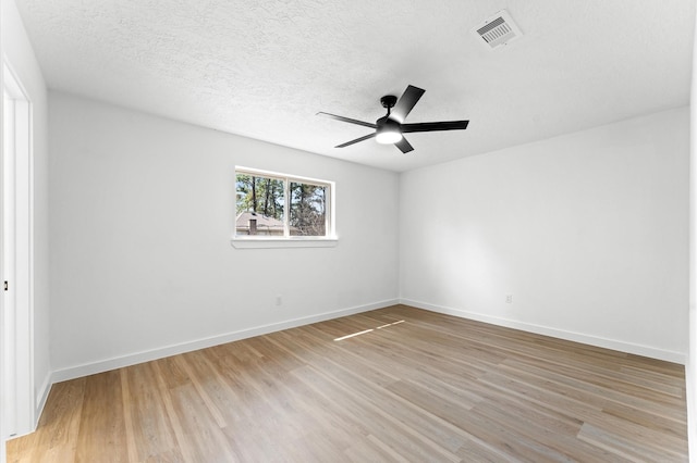 empty room with a ceiling fan, visible vents, light wood-style flooring, and baseboards