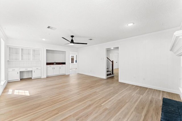 unfurnished living room with a sink, visible vents, ornamental molding, light wood-type flooring, and built in study area