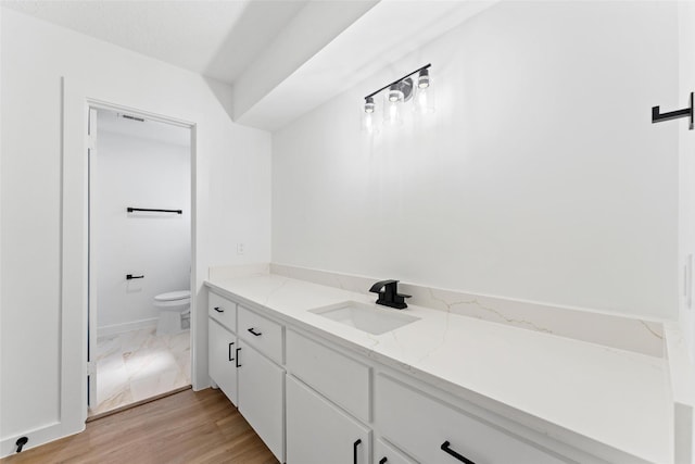 bathroom with toilet, wood finished floors, and vanity