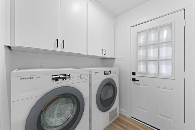 laundry room with cabinet space, light wood-style floors, and washing machine and clothes dryer