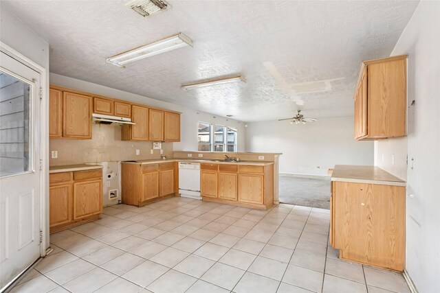 kitchen featuring visible vents, white dishwasher, a sink, a peninsula, and under cabinet range hood