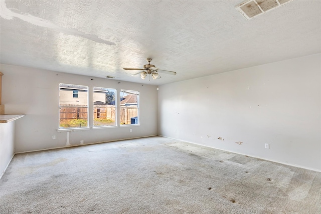 empty room with ceiling fan, visible vents, a textured ceiling, and light colored carpet