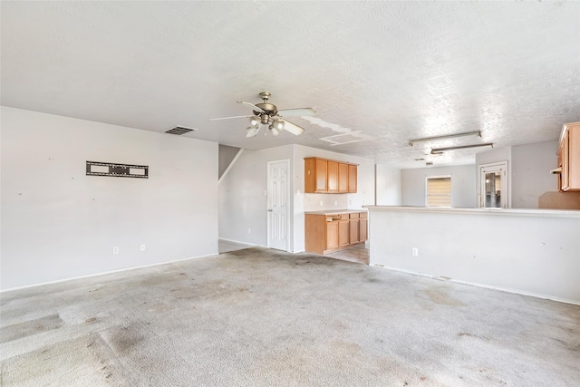 unfurnished living room featuring visible vents, ceiling fan, light carpet, and a textured ceiling