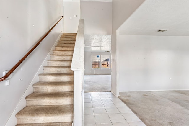 staircase with carpet, visible vents, baseboards, and tile patterned floors