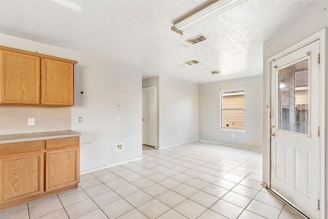 kitchen featuring light tile patterned floors, visible vents, light countertops, and a textured ceiling