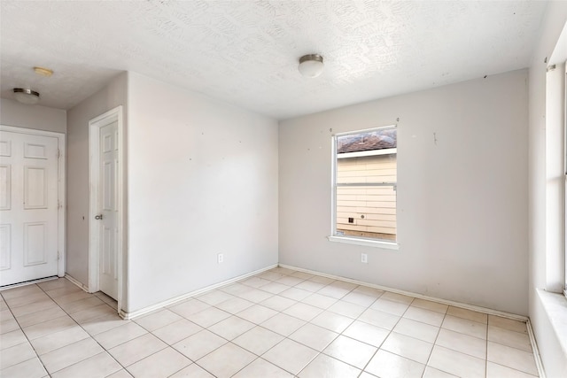 unfurnished room featuring a textured ceiling and light tile patterned floors