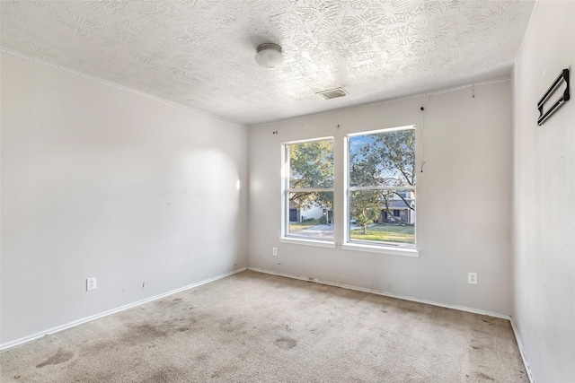 unfurnished room featuring a textured ceiling, baseboards, visible vents, and light colored carpet