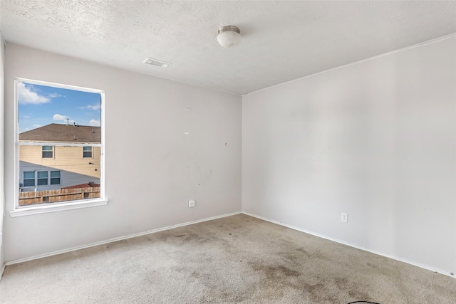 spare room with carpet floors, a textured ceiling, and baseboards