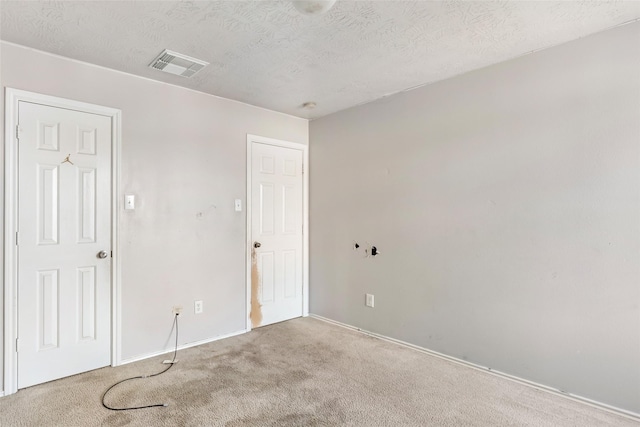 unfurnished room featuring carpet, visible vents, and a textured ceiling